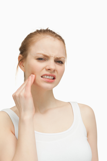 Young woman massaging her jaw against white background