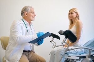 A doctor discusses dental treatment with a woman seated in a chair in Frisco.